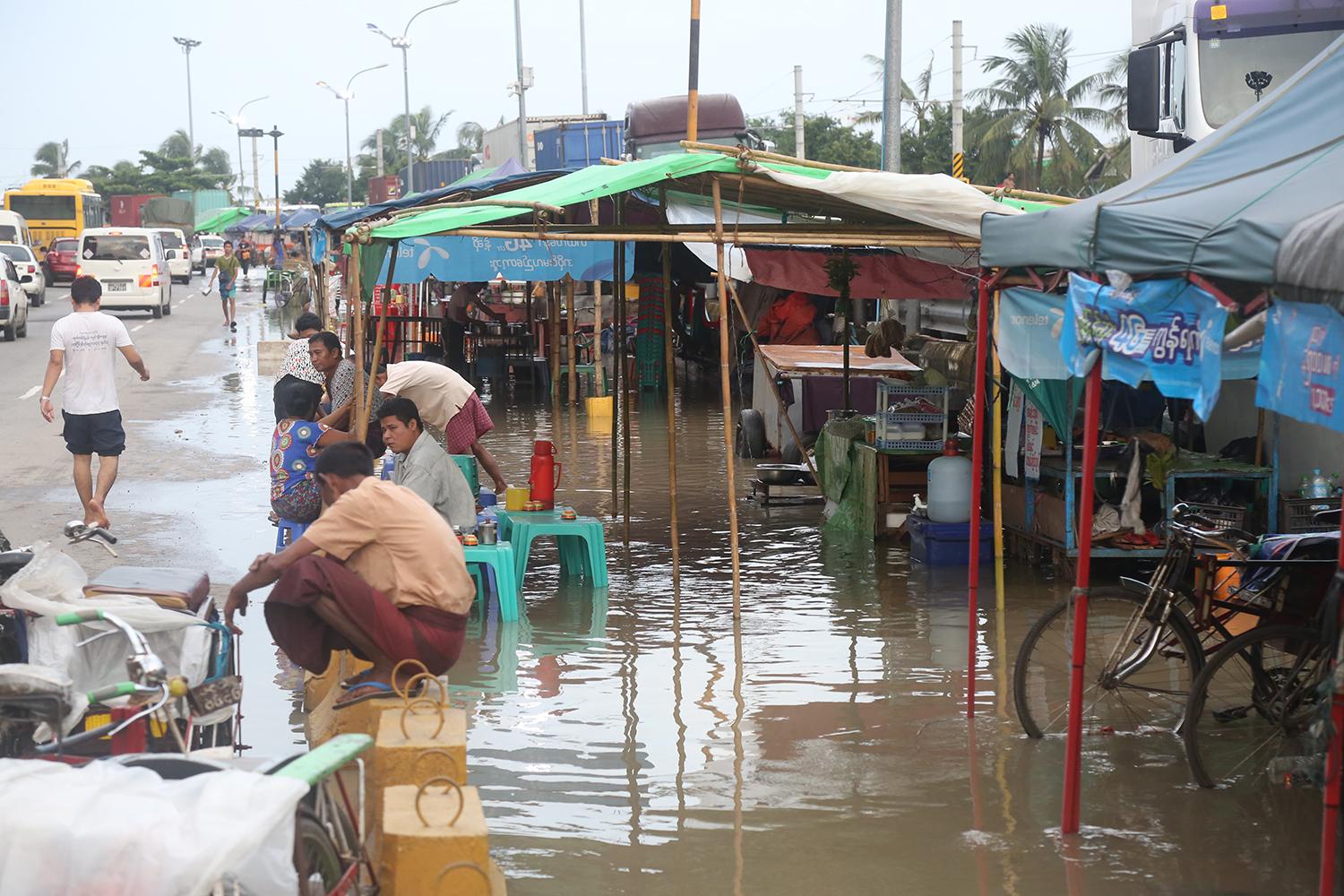 ရန်ကုန်မြို့ ကမ်းနားလမ်း ညစျေးတန်းတွင် မိုးရွာပြီးနောက် စျေးသည်များ ရေထဲတွင် စျေးရောင်းနေရစဉ် (ဓာတ်ပုံ-ကြည်နိုင်)