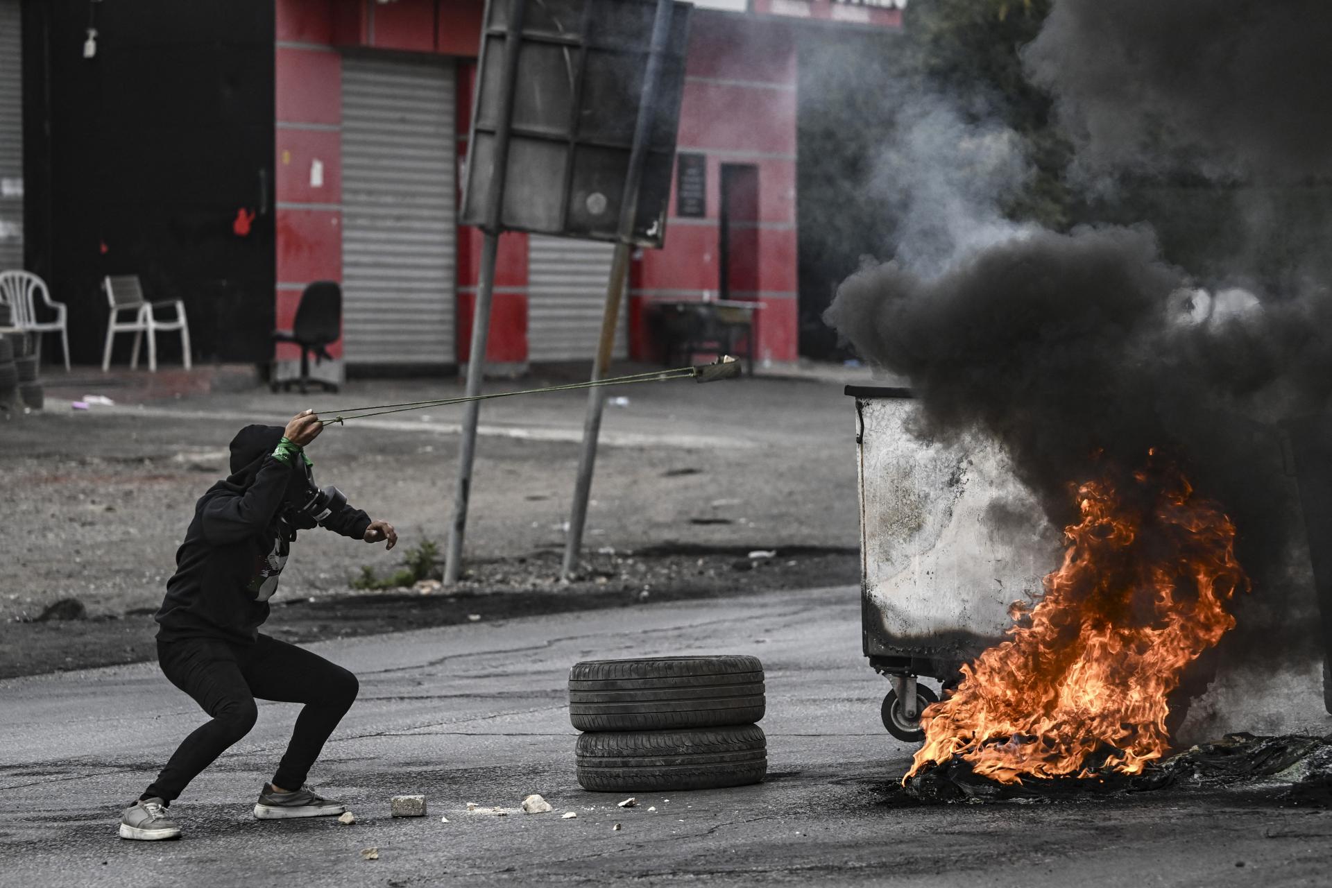 အောက်တိုဘာ ၂၇ ရက်က အယ်-ဘီရာမြို့တွင် အစ္စရေးတပ်ဖွဲ့ဝင်များအား ခဲဖြင့်ပစ်ပေါက်နေသည့် ပါလက်စတိုင်းဆန္ဒပြသူတစ်ဦးကို တွေ့ရစဉ် (Photo - AFP)