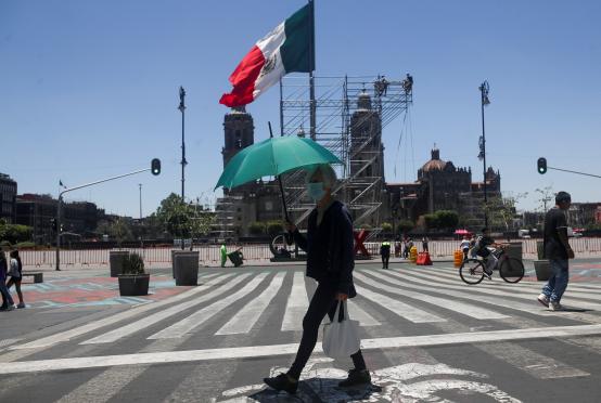 ဇွန် ၁၃ ရက်က မက္ကဆီကိုစီးတီးမြို့တော်တွင် အပူချိန်များမြင့်တက်နေချိန်အတွင်း ထီးဆောင်းပြီး လမ်းလျှောက်နေသည့် အမျိုးသမီးတစ်ဦးကို တွေ့ရစဉ်(Photo:Reuters)