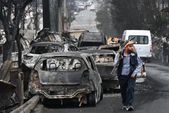 ဗီနာဒယ်မား၌ မီးလောင်ပျက်စီးနေသော ကားများ၏ဘေးမှ အမျိုးသားတစ်ဦး ဖြတ်လျှောက်လာပုံကို ဖေဖော်ဝါရီ ၄ ရက်တွင် တွေ့ရစဉ်(Photo: AFP)