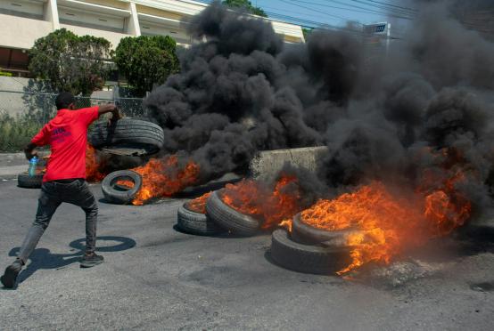 မတ် ၁၂ ရက်က ပို့အော်ပရင့်စ်မြို့တော်တွင် ဝန်ကြီးချုပ်အားဆန့်ကျင်သည့် ဆန္ဒပြသူတစ်ဦးက လမ်းပေါ်တွင် တာယာများကို မီးရှို့နေစဉ်