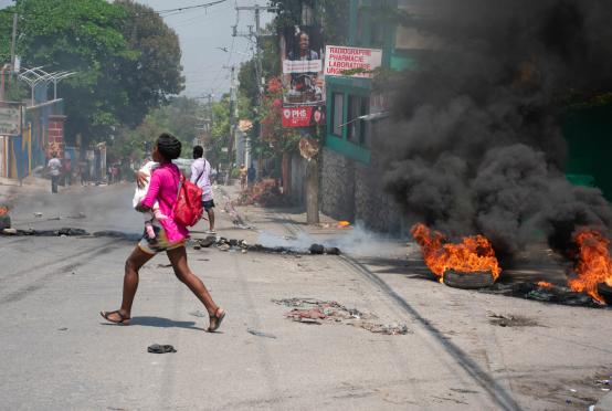 ပို့အော်ပရင့်၌ သေနတ်သံများကြားရပြီးနောက် ကလေးချီ၍ ပြေးနေသော အမျိုးသမီးကို မတ် ၂၀ ရက်တွင် တွေ့ရစဉ် (Photo: AFP)