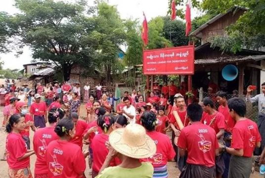 ရွာသစ်ကုန်းကျေးရွာတွင် NLD ပါတီ ဆိုင်းဘုတ်တင်အခမ်းအနားပြုလုပ်နေမှုကို တွေ့ရစဉ်