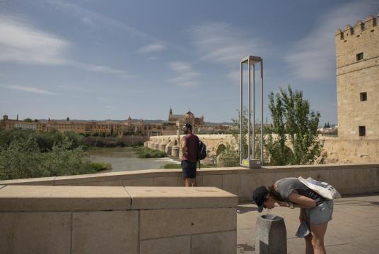 ဧပြီ ၂၇ ရက်က စပိန်နိုင်ငံ ကော်ဒိုဘာတွင် အပူလှိုင်းကျစဉ် အမျိုးသမီးတစ်ဦ်း ရေပန်းမှ ရေကို သောက်နေပုံအားတွေ့ရစဉ် (Photo – AFP)