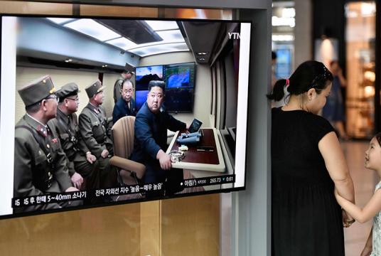  စွယ်စုံသုံး ဒုံးပစ်လောင်ချာ စမ်းသပ်မှုအား မြောက်ကိုရီးယားခေါင်းဆောင် ကင်ဂျုံအွန်က ကြီးကြပ်မှုသတင်းကို ဆိုးလ်ရှိဘူတာရုံတွင် သြဂုတ် ၁ ရက်၌ ထုတ်လွှင့်နေစဉ်