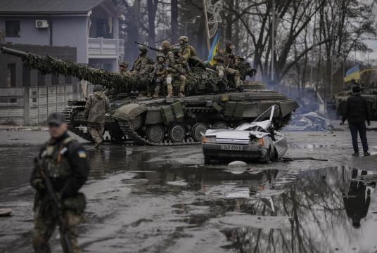 Photo: AP ဧပြီ ၂ ရက်က ကိယက်ဗ်မြို့ပြင်တွင် သေဆုံးနေသည့် ယာဉ်မောင်းသူ ရှိနေဆဲ အရပ်သားကားတစ်စီးအား ယူကရိန်းစစ်သားများက တင့်ကားဖြင့် ဖြတ်သန်းသွားစဉ်