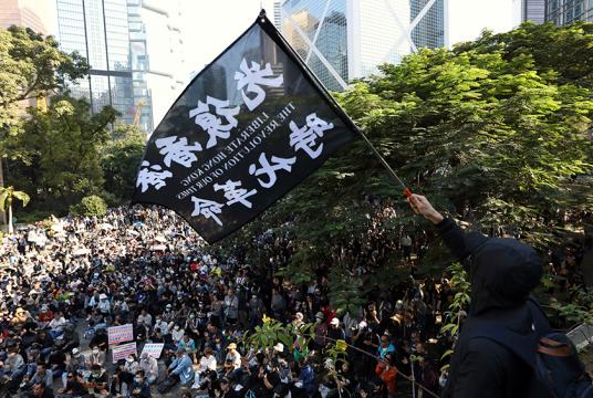 နိုဝင်ဘာ ၃၀ တွင် ဟောင်ကောင်၌ ကျောင်းသားများနှင့် သက်ကြီးပိုင်းများအတွက် စုဝေးမှုတစ်ခုအတွင်း ဆန္ဒပြသူတစ်ဦးက အလံဝှေ့ယမ်းနေစဉ် (Photo: AP)