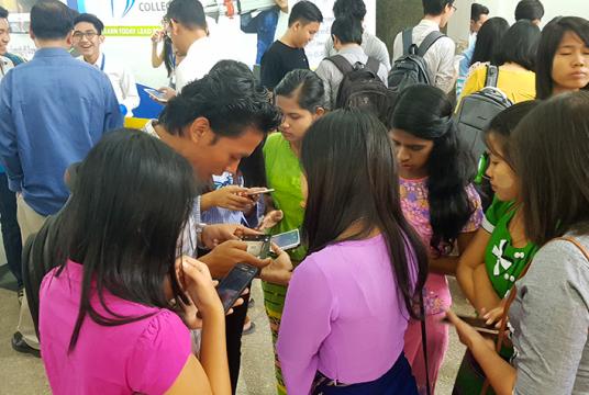 တယ်လီဖုန်းအသုံးပြုနေသူ လူငယ်များကို ရန်ကုန်မြို့လယ်တစ်နေရာတွင် တွေ့ရစဉ်