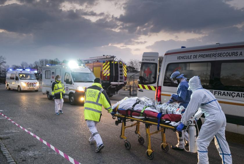 ၂၀၂ဝပြည့်နှစ် မတ် ၂၉ ရက်က ပြင်သစ်နိုင်ငံမြူးဟောက်စ်မြို့တွင် COVID-19 လူနာတစ်ဦးအား ဆေးရုံကားဆီသို့ လူနာတင်တွန်းလှည်းဖြင့် သယ်ဆောင်လာစဉ် (Photo: AFP)