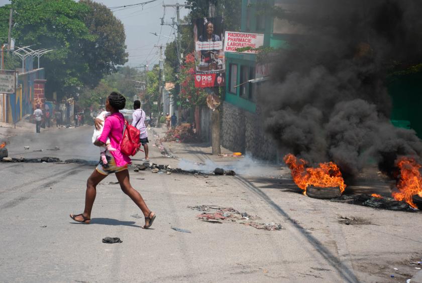 ပို့အော်ပရင့်၌ သေနတ်သံများကြားရပြီးနောက် ကလေးချီ၍ ပြေးနေသော အမျိုးသမီးကို မတ် ၂၀ ရက်တွင် တွေ့ရစဉ် (Photo: AFP)