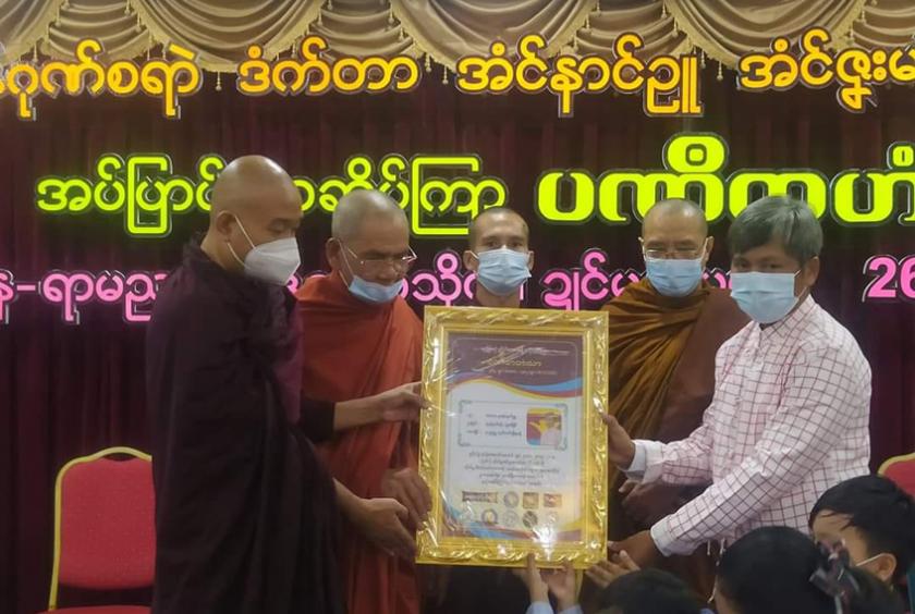 မွန်လူမှု အဖွဲ့အစည်းများက ချီးမြှင့်သည့် ဆုတံဆိပ်အား ဒေါက်တာအောင်နိုင်ဦး လက်ခံရယူနေစဉ်