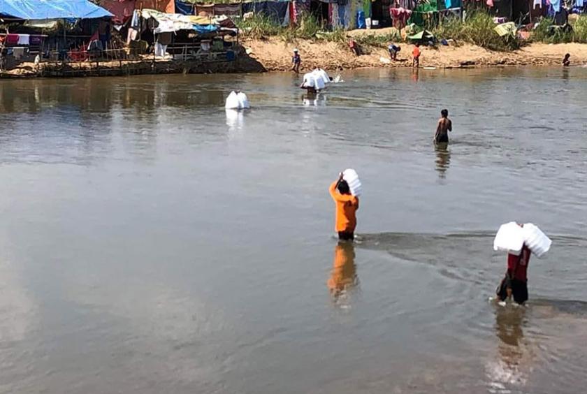 သောင်ရင်းမြစ်ကမ်းစပ် မြန်မာဘက်ခြမ်းတွင် စစ်ဘေးရှောင်များအား ထိုင်းဘက်မှ ပရဟိတအဖွဲ့များက အသင့်စားထမင်းဘူးများပေးပို့စဉ် (ဓာတ်ပုံ-ကိုကြီးမန်း)၊