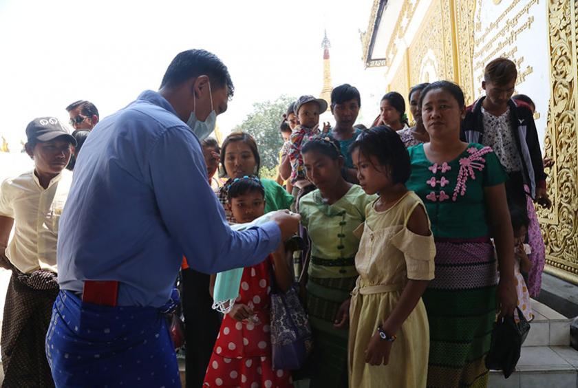 ရွှေတိဂုံစေတီတော်သို့ လာရောက်ဖူးမြော်သူများအား Mask များ ဝေငှနေမှုကို တွေ့ရစဉ် (ဓာတ်ပုံ-ကြည်နိုင်)