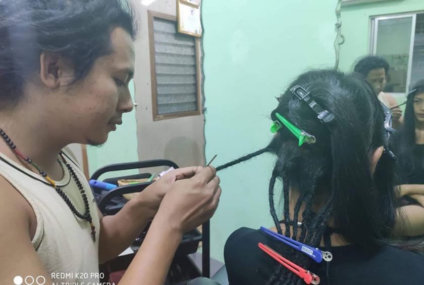 မိန်းကလေးတစ်ဦးအား Dreadlocks Hair Style ဆံပင်ကျစ်ပေးနေစဉ်
