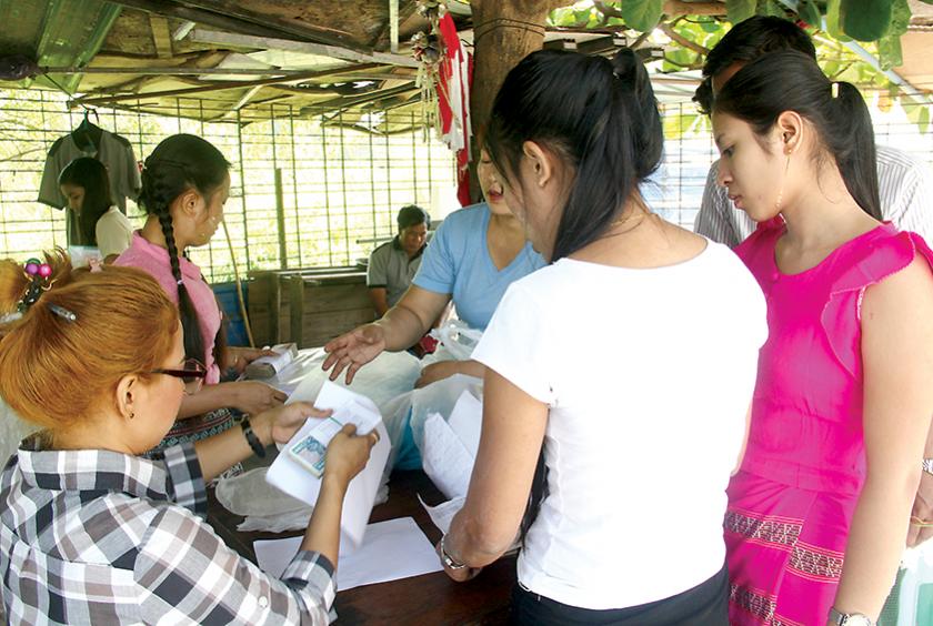 လှိုင်သာယာစက်မှုဇုန်ရှိ လက်ဝါးအထည်ချုပ်စက်ရုံ (၃) ယာယီပိတ်သဖြင့် အလုပ်သမားများအား နစ်နာကြေး ပေးနေသည်ကို မတ် ၁၁ ရက်က တွေ့ရစဉ် (ဓာတ်ပုံ-ရှိုင်းလင်းအောင်)
