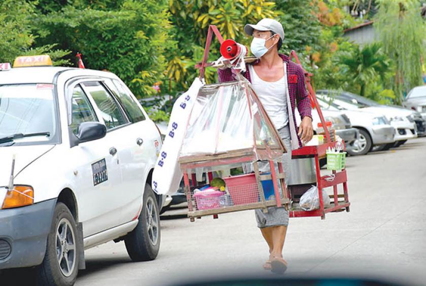 စျေးသည်တစ်ဦး ရန်ကုန်မြို့ရှိ ရပ်ကွက်တစ်ခုအတွင်း စျေးလှည့်လည်ရောင်းချနေစဉ် (ဓာတ်ပုံ- ကြည်နိုင်)